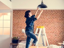 Woman installing new light in home