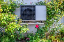 modern outdoor module of heat pump heating surrounded by roses