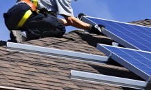 Solar service technician on roof performing maintenance on solar pv system