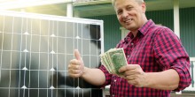man giving thumbs up holding money next to solar panel