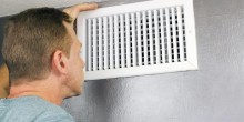 man inside home inspecting a vent