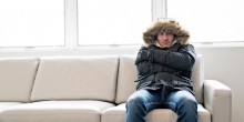man in a winter coat angrily sitting on a couch
