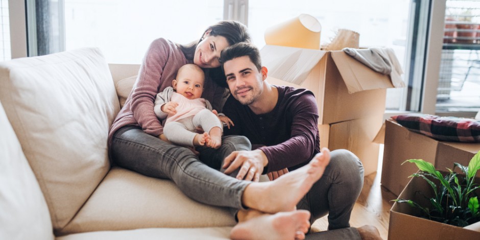 young family on couch with baby with moving boxes