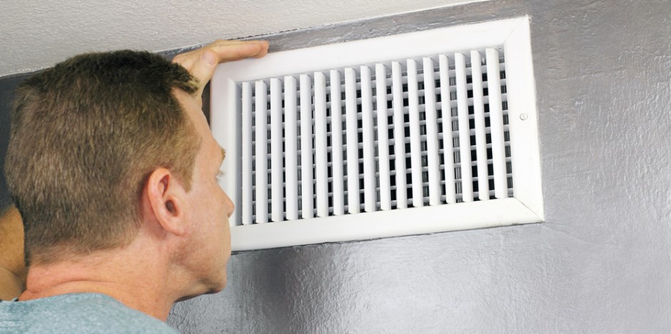 man inside home inspecting a vent