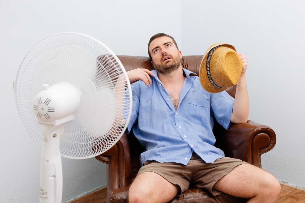 man at home sitting in front of fan, too hot