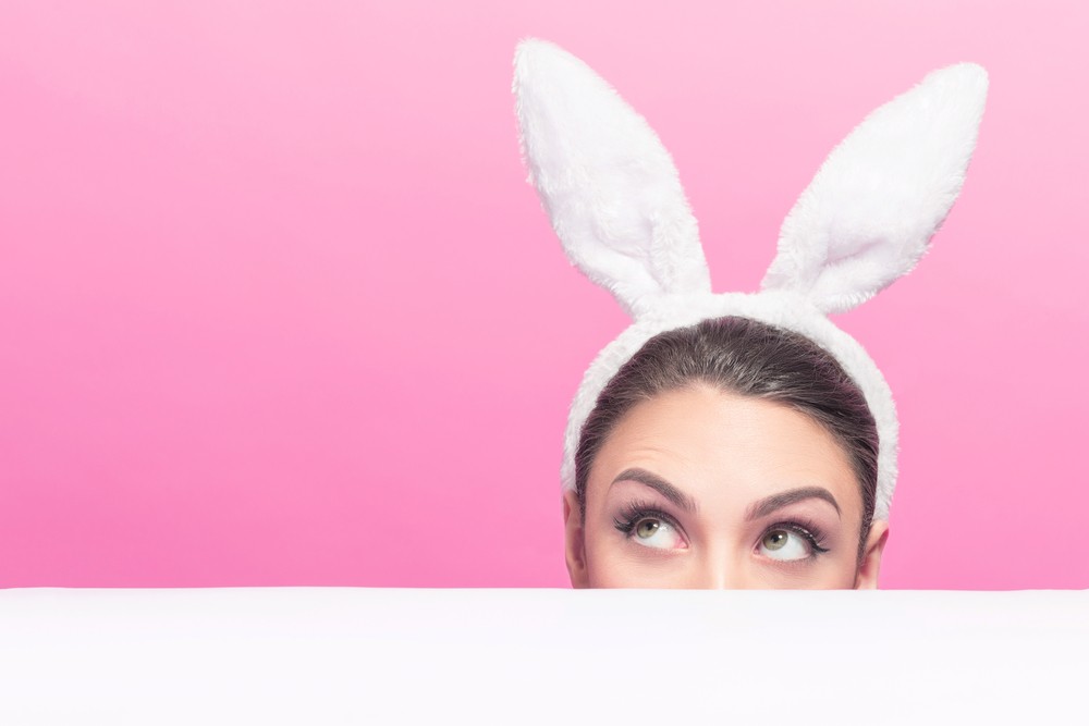 woman peeking over table with bunny ears on
